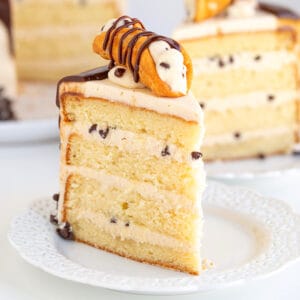 square image of a slice of vanilla cake with a cannoli cream filling on a white lace plate