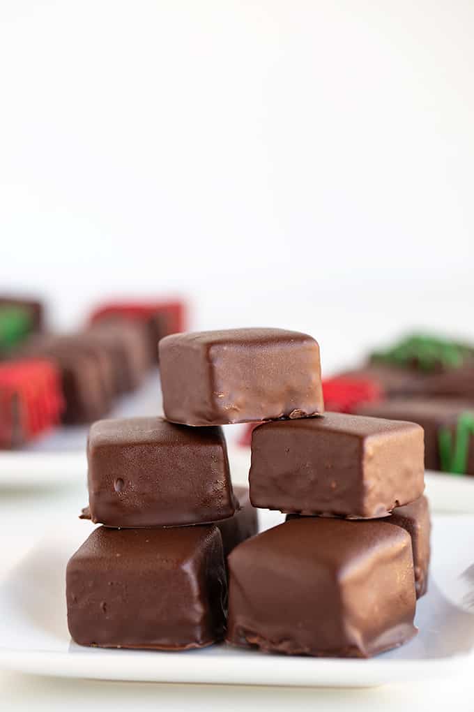 stack of candies on a white plate with other candies behind it in red and green