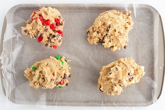 varieties of chocolate chip cookies on a wax paper lined baking sheet