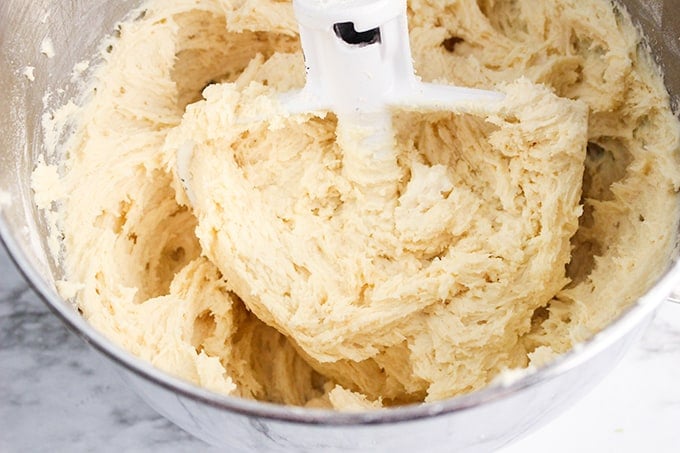 cookie dough in a metal bowl with a white paddle attachment