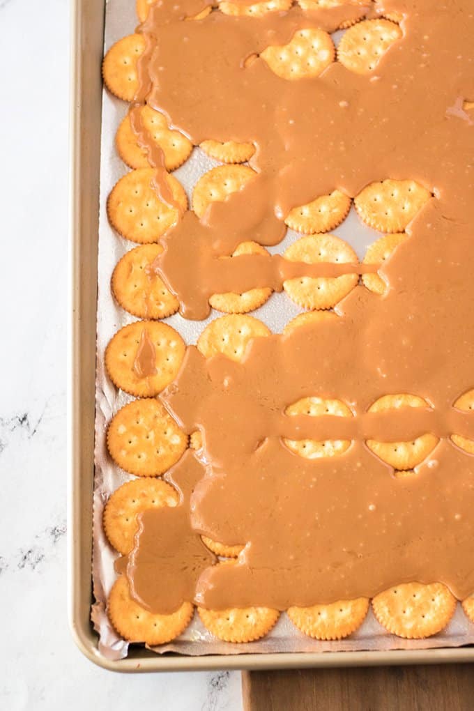 toffee poured over ritz crackers on a foil lined baking tray