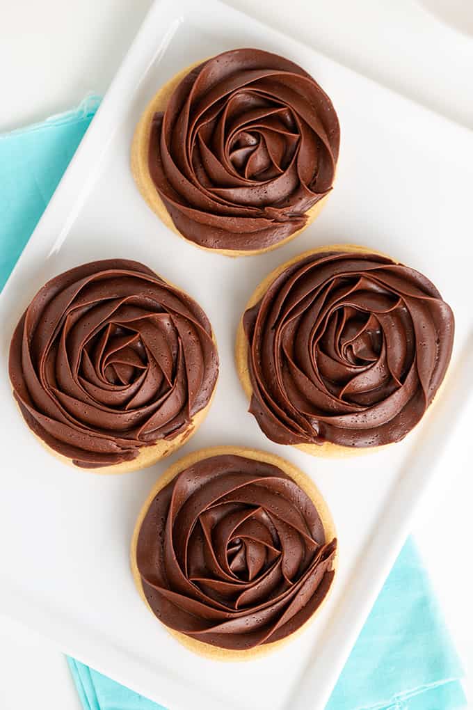 overhead photo of 4 chocolate frosted peanut butter cookies on a white rectangle plate