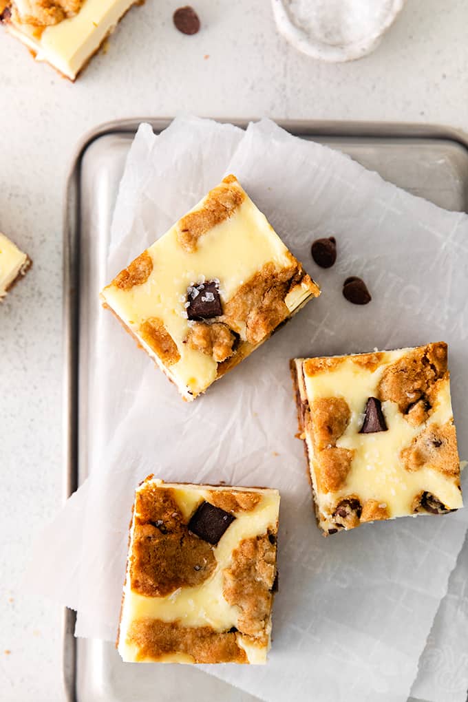 overhead close up photo of the bars showing the baked cookie and cheesecake tops on parchment paper