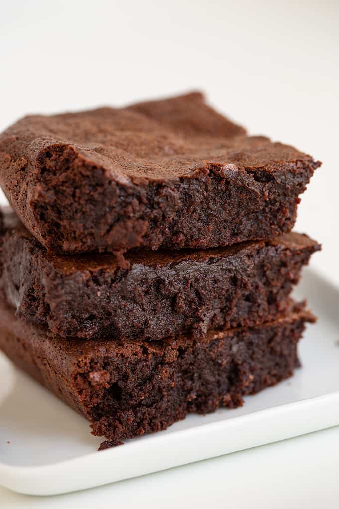 Close-up of three homemade brownies stacked on a plate.