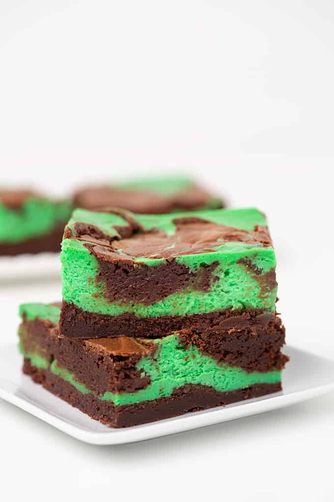 mint cheesecake brownies on a white surface with a small white plate