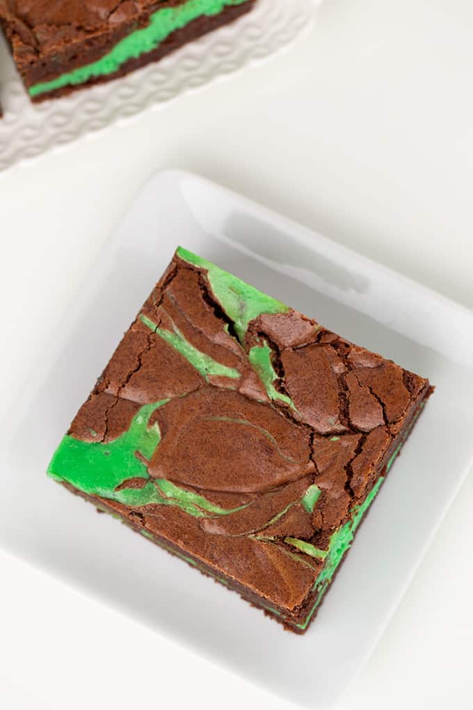 overhead photo of mint brownies on a square plate on a white surface