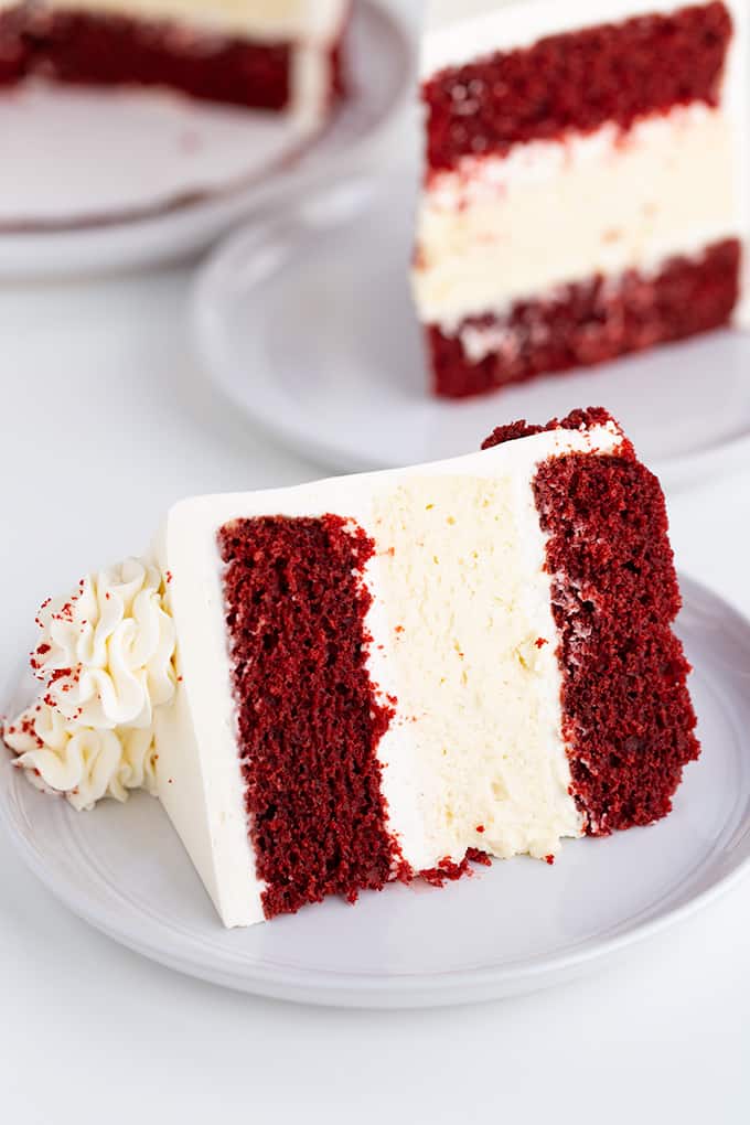 cheesecake cake on a white plate on a white surface with a second slice behind it