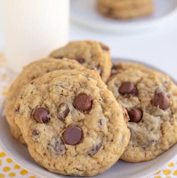 banana chocolate chip cookies on a small plate with a glass of milk behind it
