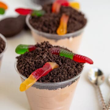plastic up filled with chocolate mousse and crushed oreos on a white surface