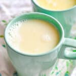 white hot chocolate on a green and white linen on a white wood surface