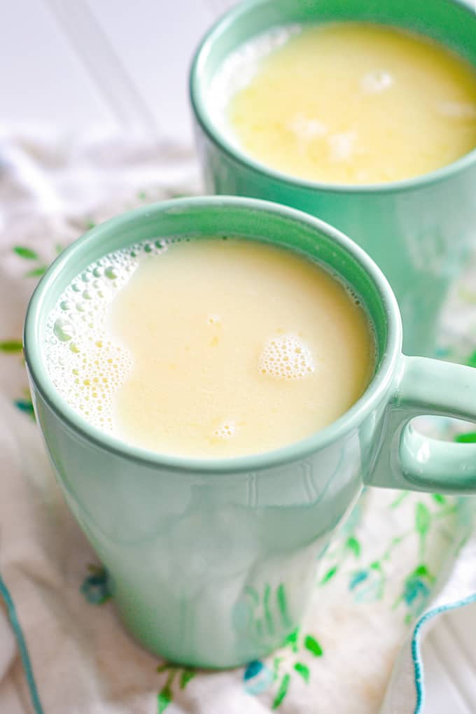 white hot chocolate on a green and white linen on a white wood surface