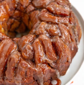 cinnamon roll monkey bread on a white platter with a orange striped towel under it