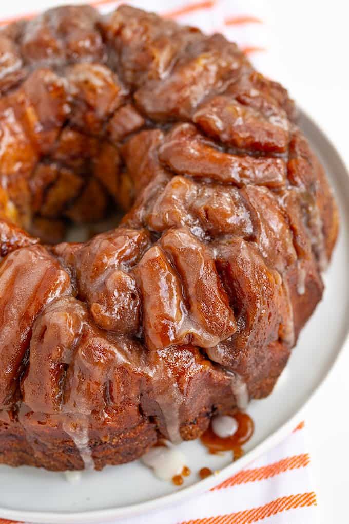 cinnamon roll monkey bread on a white platter with a orange striped towel under it