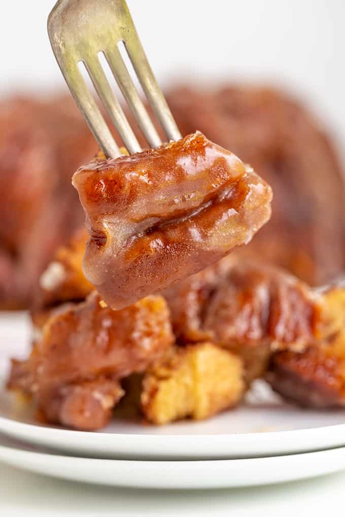 a fork holding pieces of monkey bread above a plate of pull apart bread