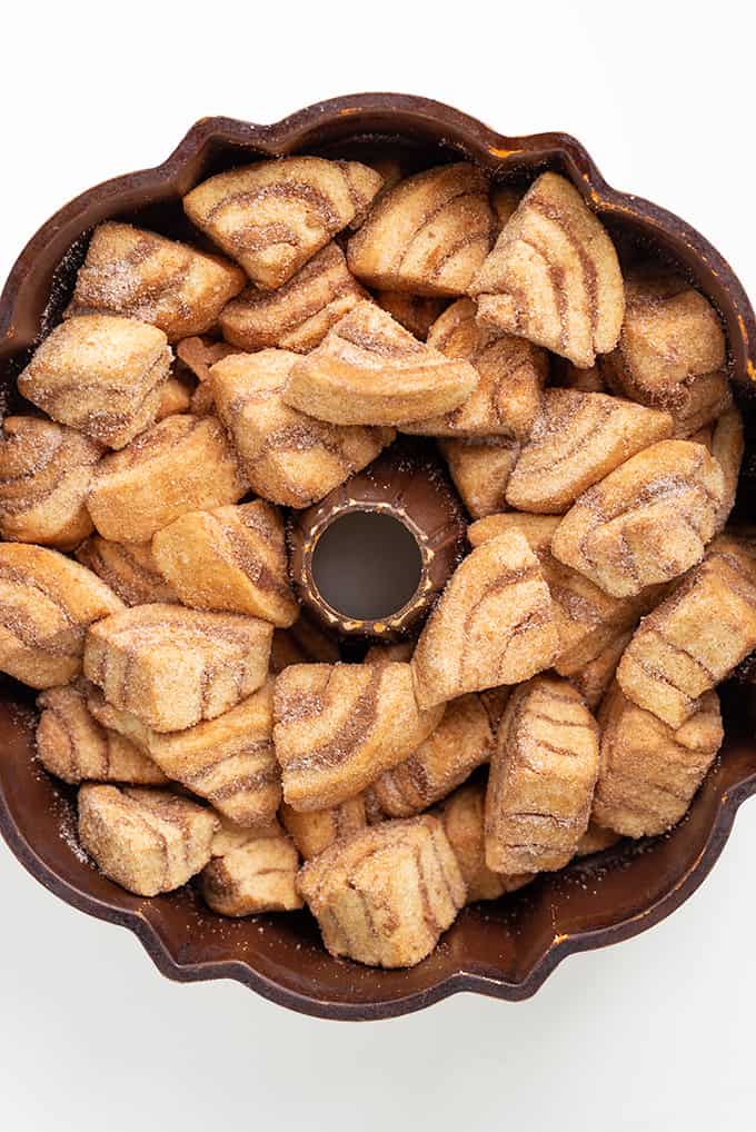 overhead image of pieces of cinnamon roll in a bundt pan on a white surface