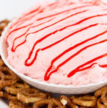 bowl of strawberry dip surrounded by pretzels on a white counter