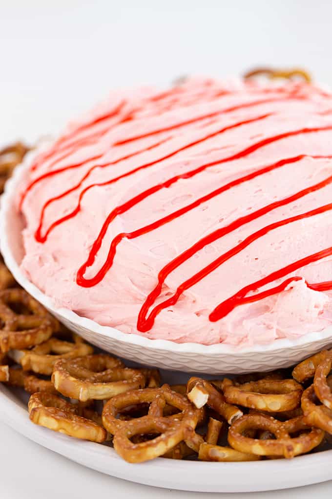 bowl of strawberry dip surrounded by pretzels on a white counter