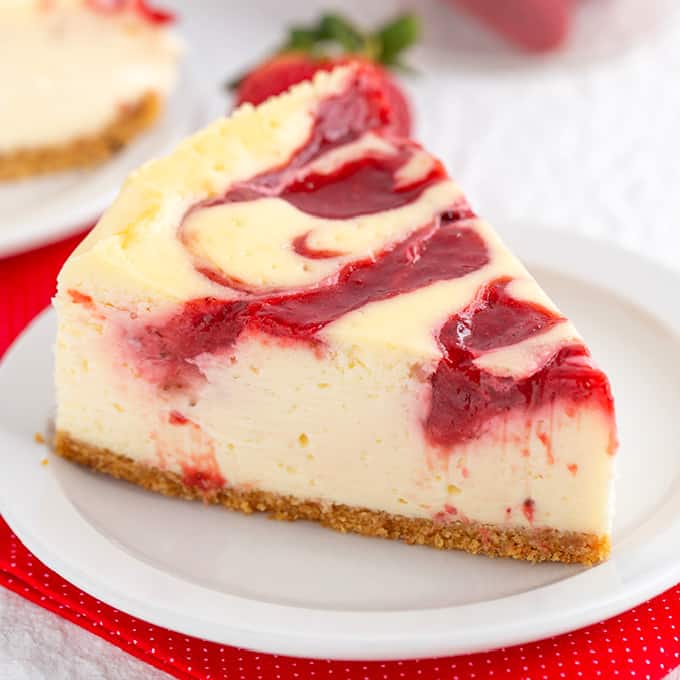 A slice of strawberry cheesecake with a cookie dough crust, served on a plate.