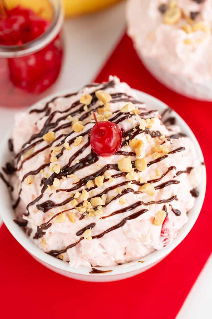 showing the toppings on the fluff salad with a jar of cherries behind it