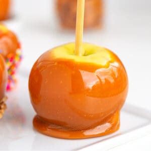 Easy caramel apples on a white plate with a candy stick.