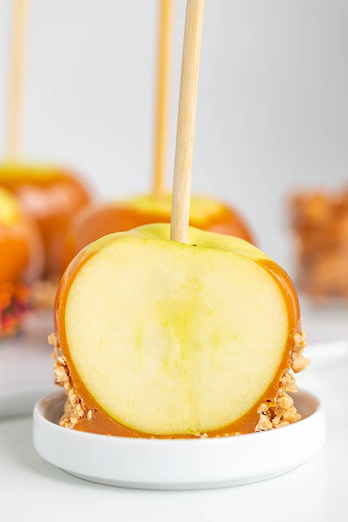 caramel apple sliced in half on a white plate