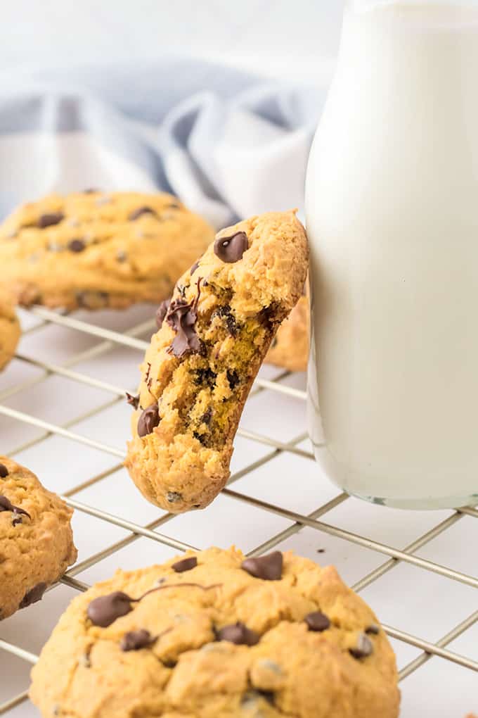 Sideways cookie leaning against a bottle of milk.