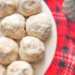 snowball cookies on a white plate with a red linen under the cake plate