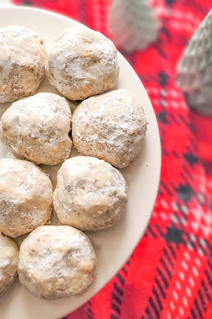 snowball cookies on a white plate with a red linen under the cake plate