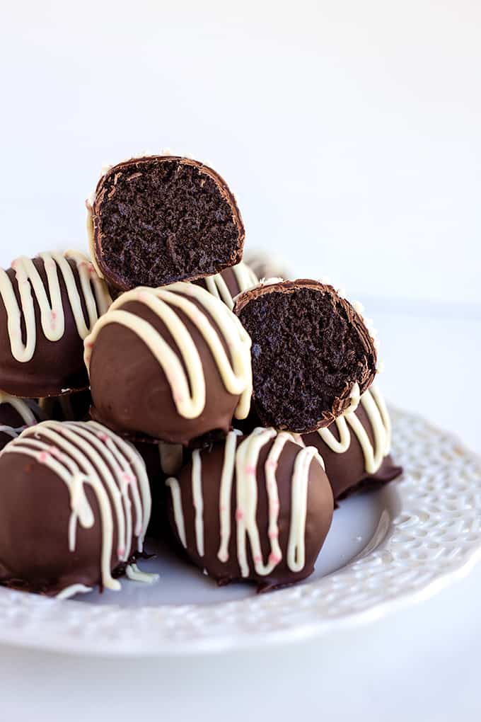 stack of peppermint oreo truffles on a white plate on a white background with an truffle cut in half