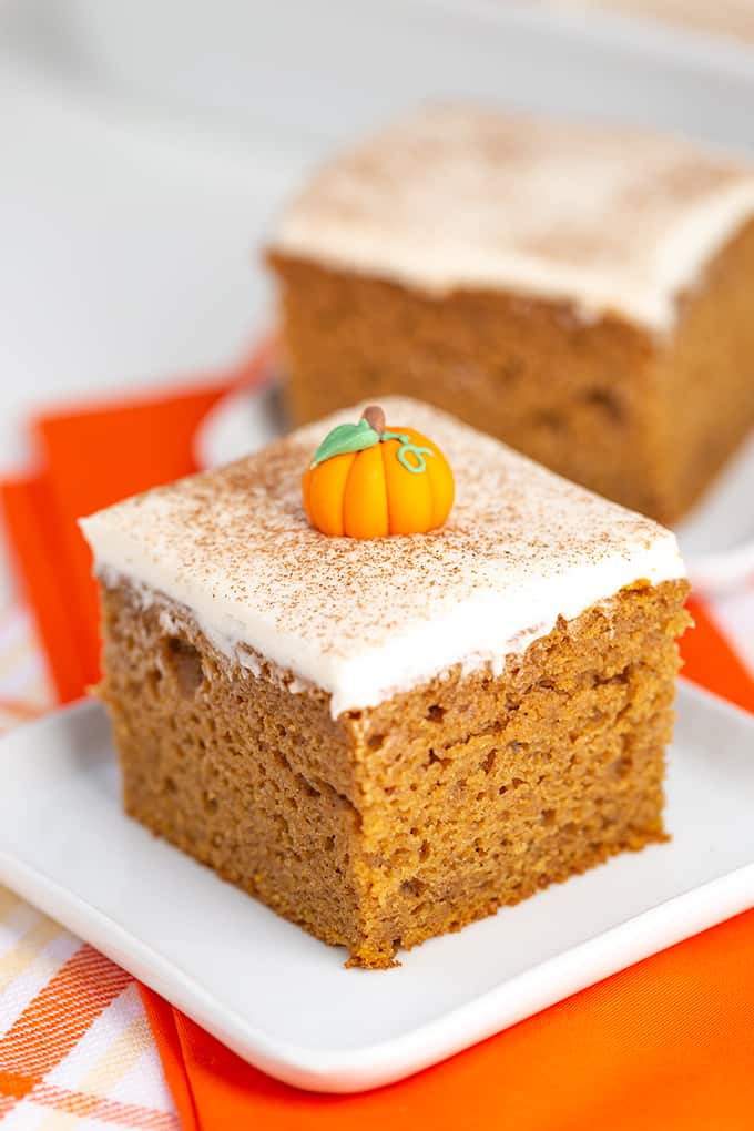 close-up view of single slice of pumpkin cake mix cake on a rimmed white plate with an orange linen under the plate