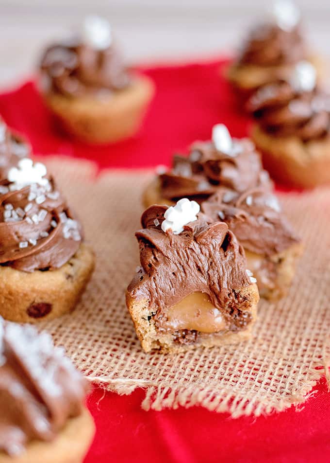 cookie cups with gooey caramel oozing out of the center on burlap and a red fabric