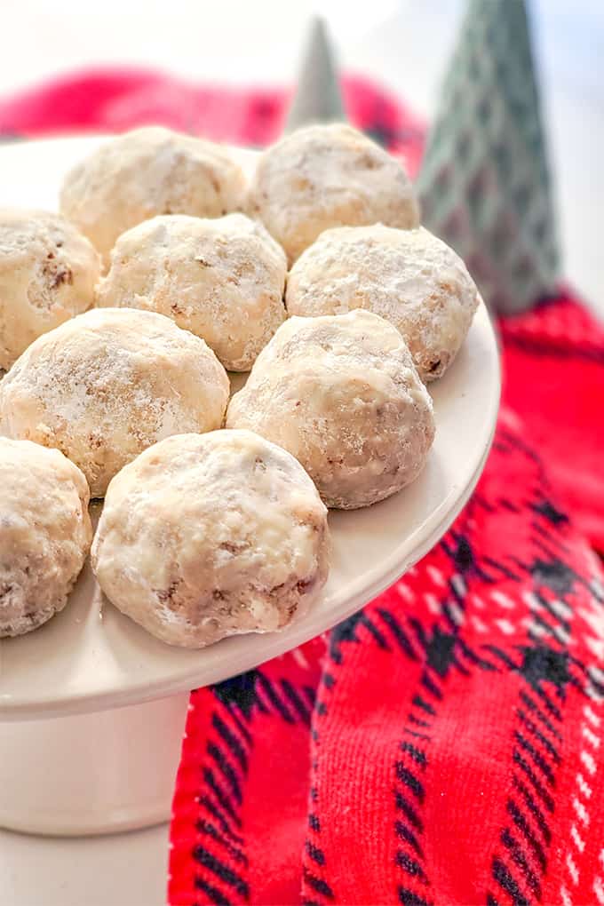 cookies on a white cake plate with a red and black fabric under the cake plate