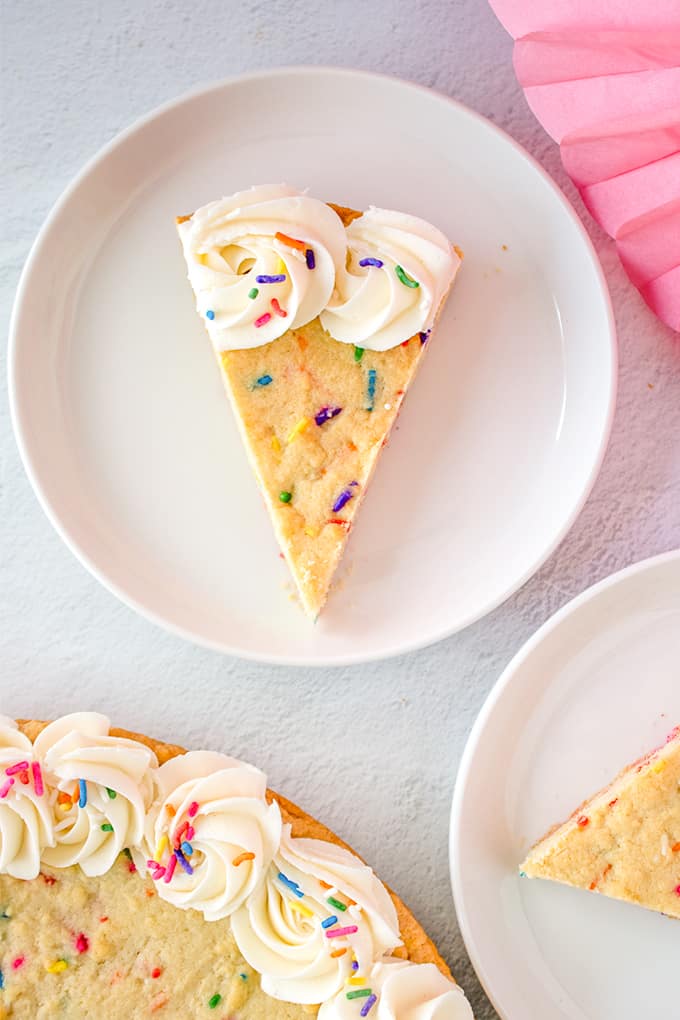 slice of sugar cookie cake on a white plate on a gray surface