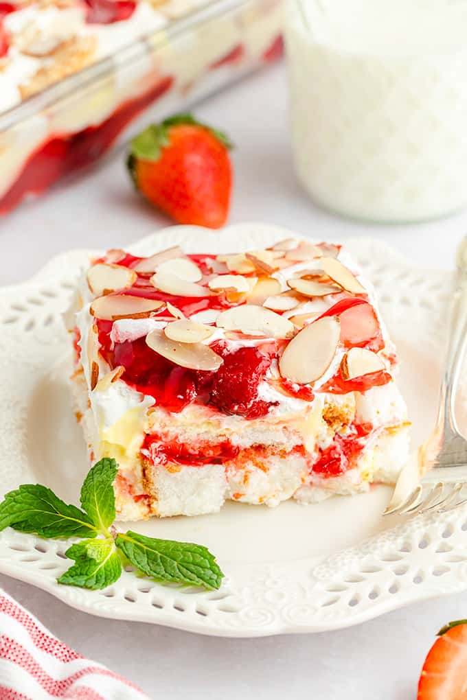 strawberry heaven on earth cake on a white dessert plate with mint leaves on the plate on a white surface