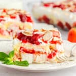 slice of strawberry layer cake on a white plate with a mint leaf