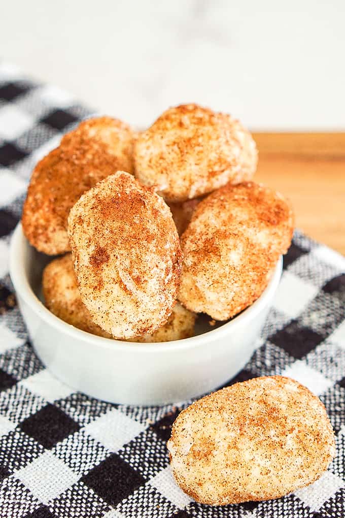 Irish Potato Candy in a small bowl with an extra candy on a checkered linen on a cutting board