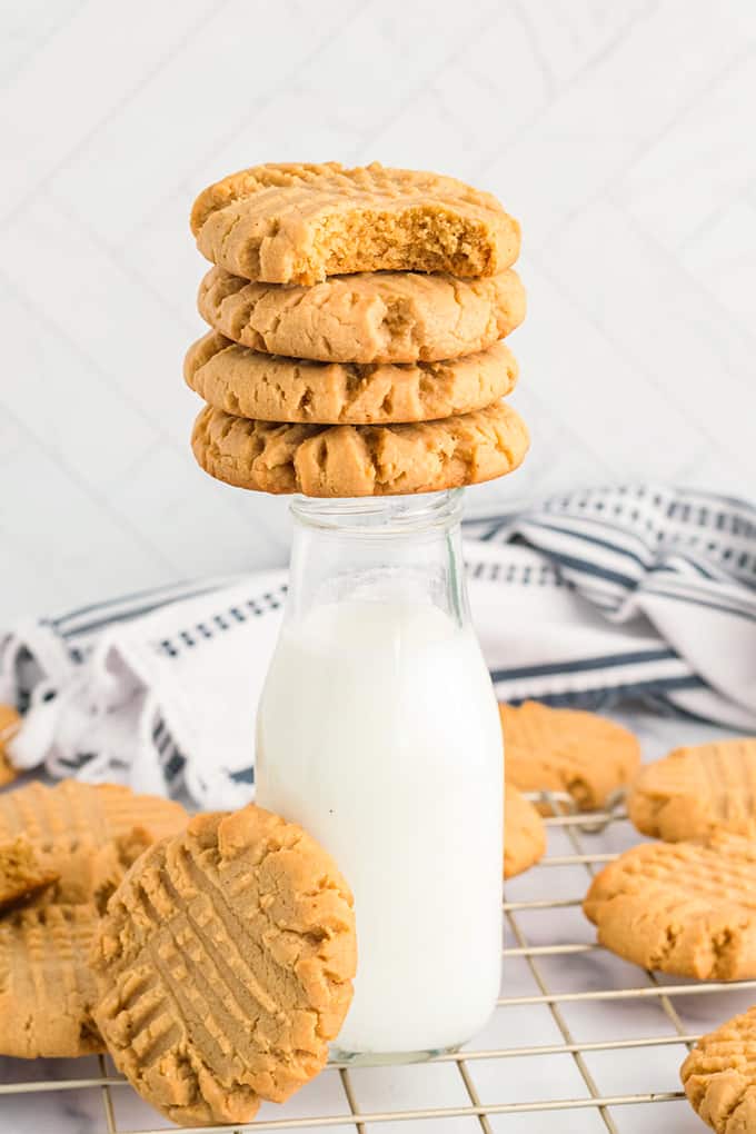 Cookies stacked on a bottle of milk. 