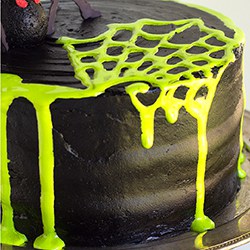 layered halloween cake with a spider web on top of black frosting