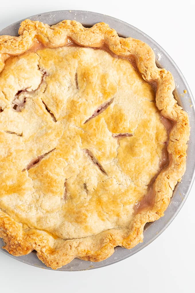 Whole rhubarb pie in a metal pie plate on a white background, close up, top down image.