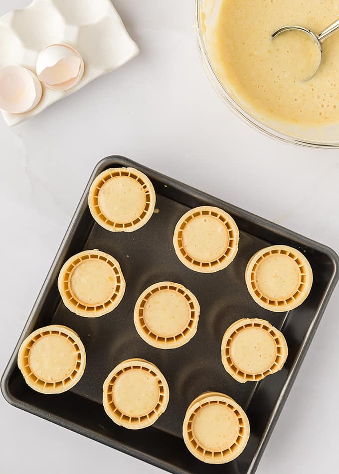 ice cream cones filled with batter in a baking dish.