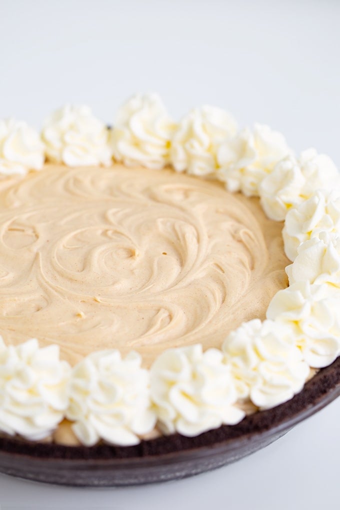 A creamy dessert featuring a peanut butter filling and a dollop of whipped cream on top in a glass pie plate