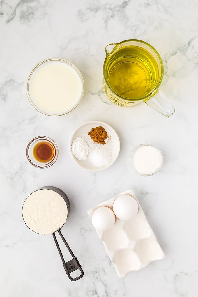 Homemade ingredients for Funnel Cakes are shown on a marble table.