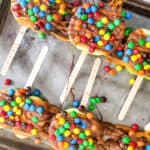 Caramel apple slices with popsicle sticks arranged on a baking sheet with parchment paper