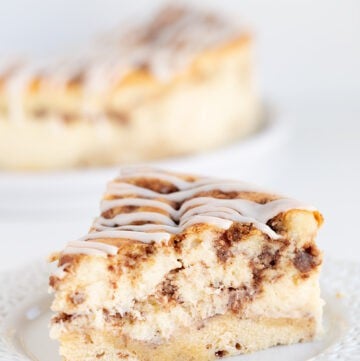 A slice of cinnamon roll cheesecake on a white plate. on a white table