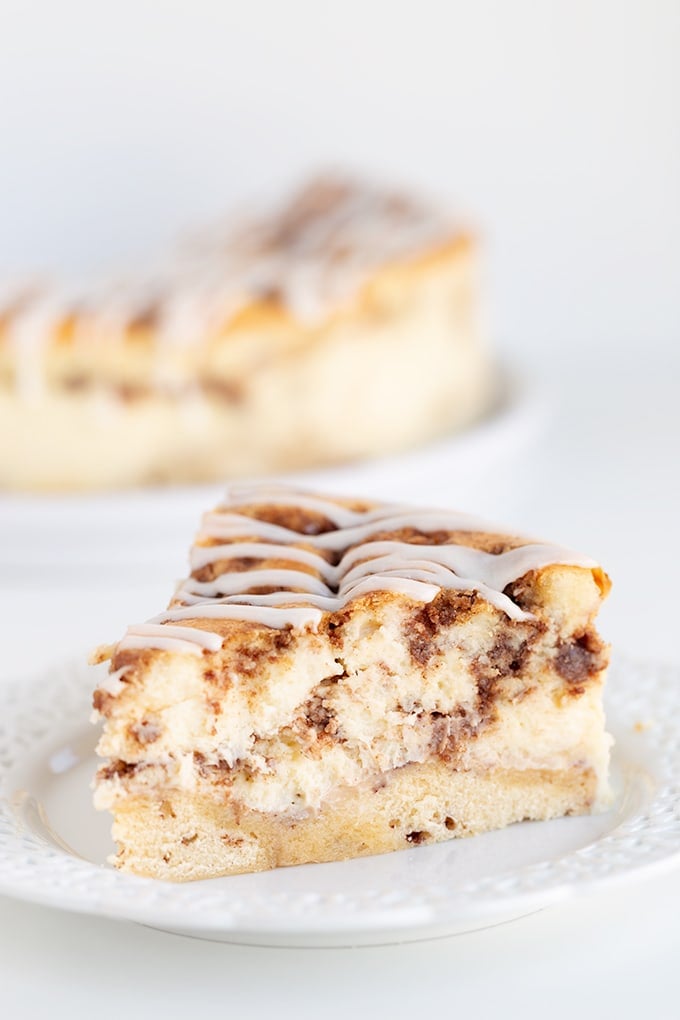 A slice of cinnamon roll cheesecake on a white plate. on a white table