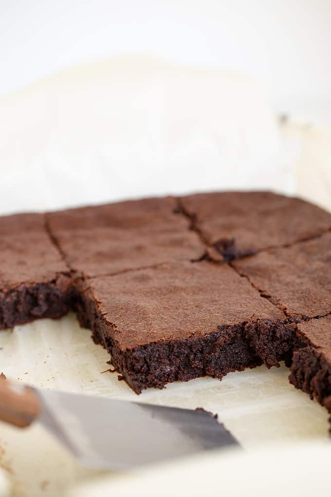 brownies made from scratch in a glass baking pan with a spatula and the brownies cut into squares