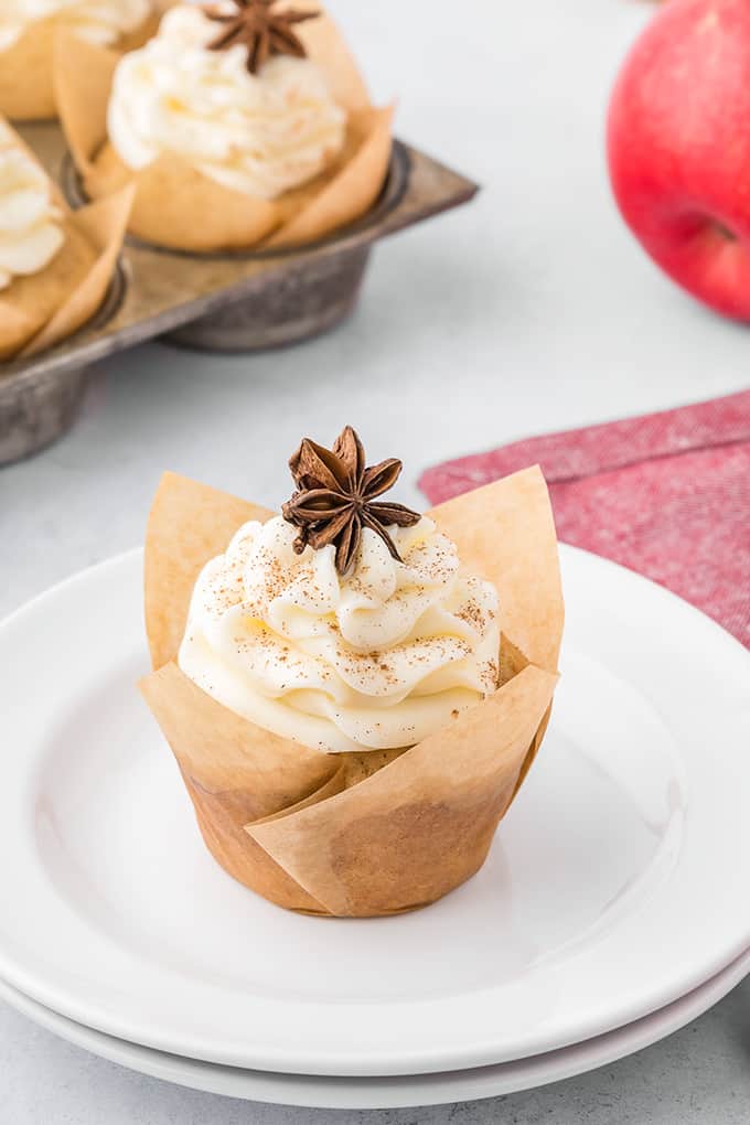 A white plate with apple cider cupcakes and apples on it.