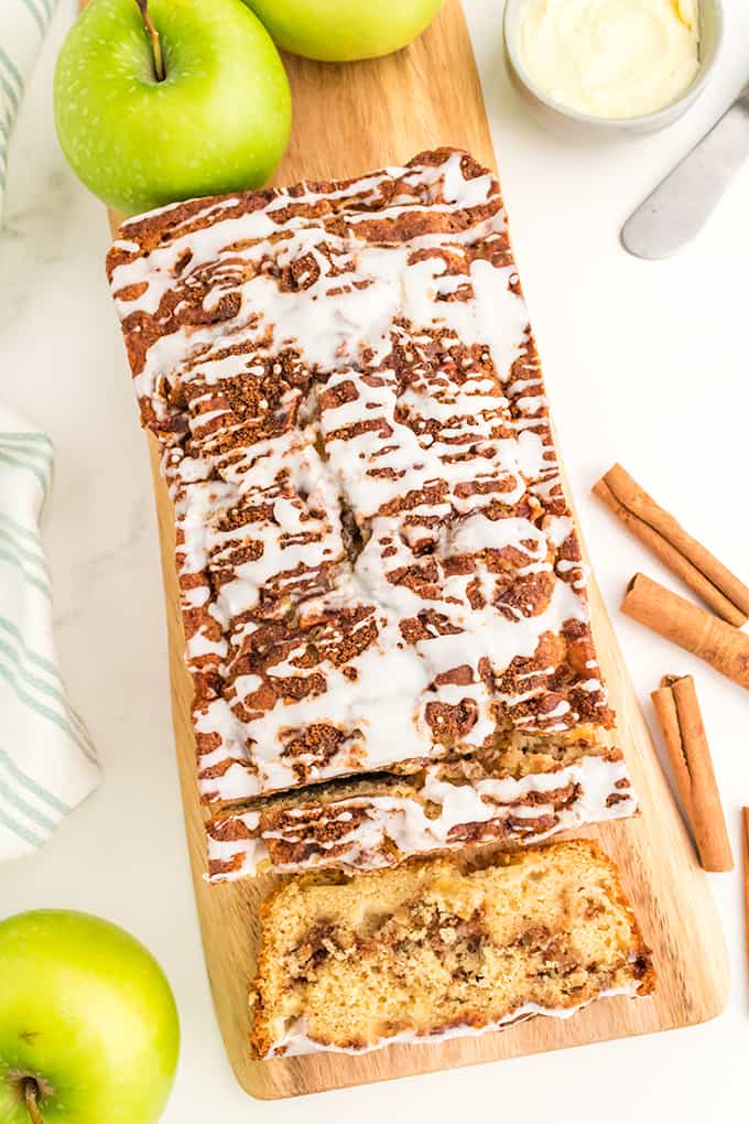 A slice of apple bread with cinnamon icing on a cutting board.