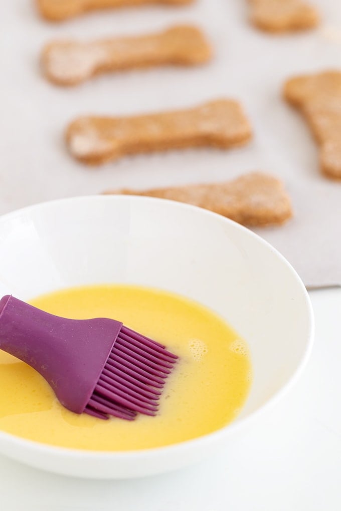 A bowl of dog biscuits with a purple brush.