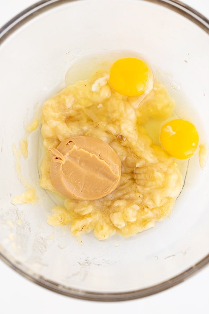 A glass bowl with eggs and peanut butter in it.